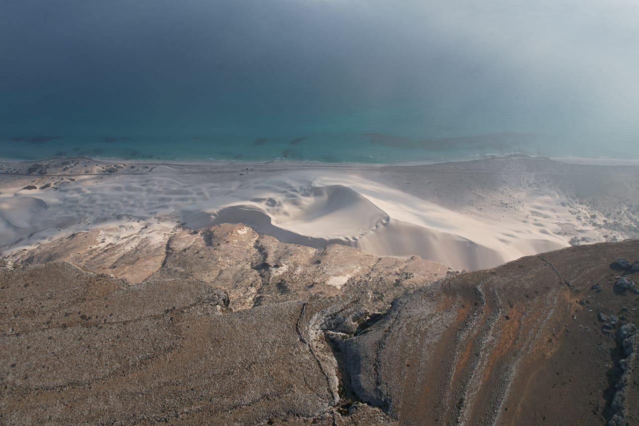 Sand dune spilling into the turquoise shallows of Socotra